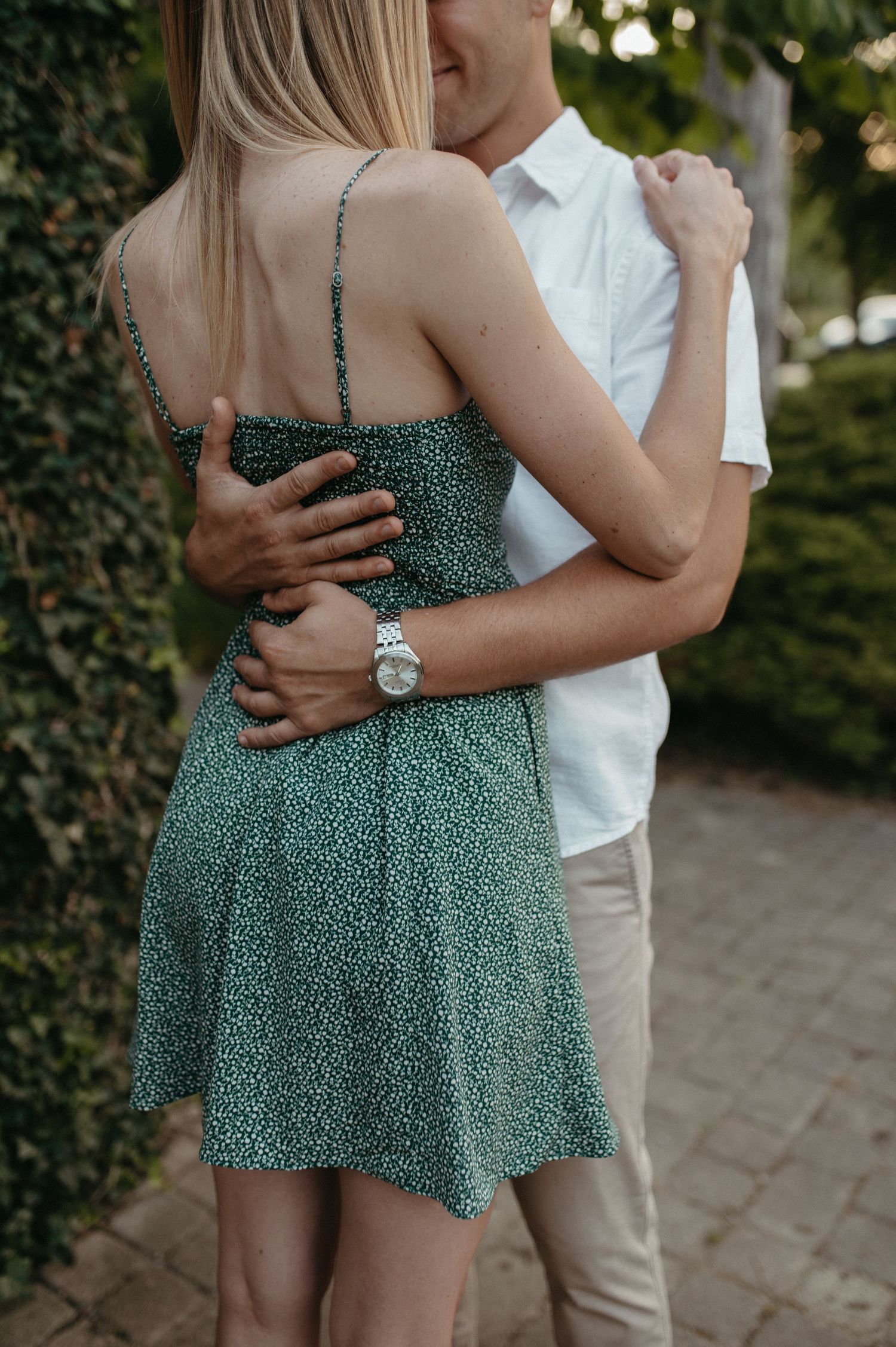 Back view of couple in embrace showing green floral dress detail and white shirt.