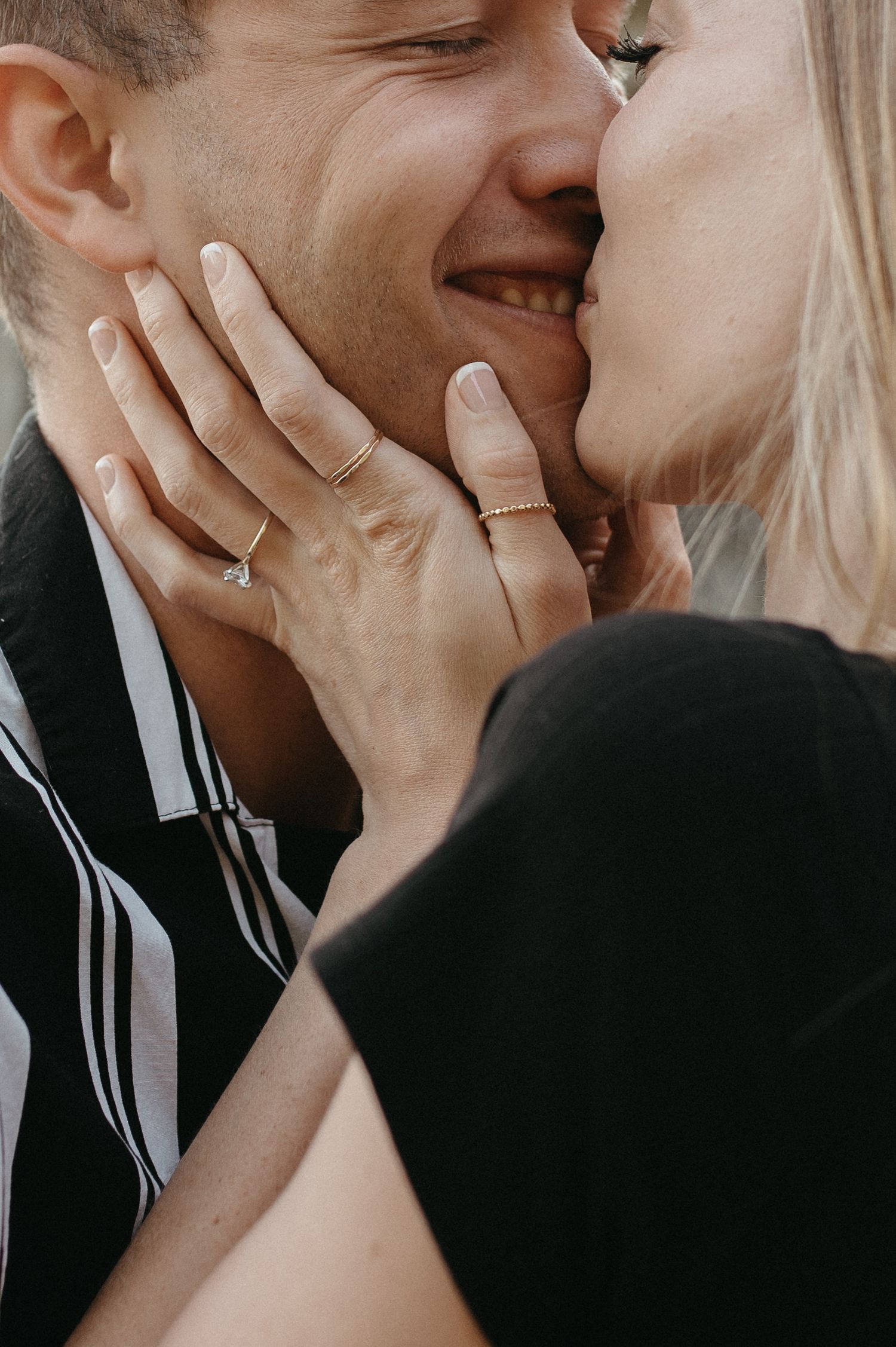 Close-up of a loving embrace showing hands with delicate rings against a blurred background.