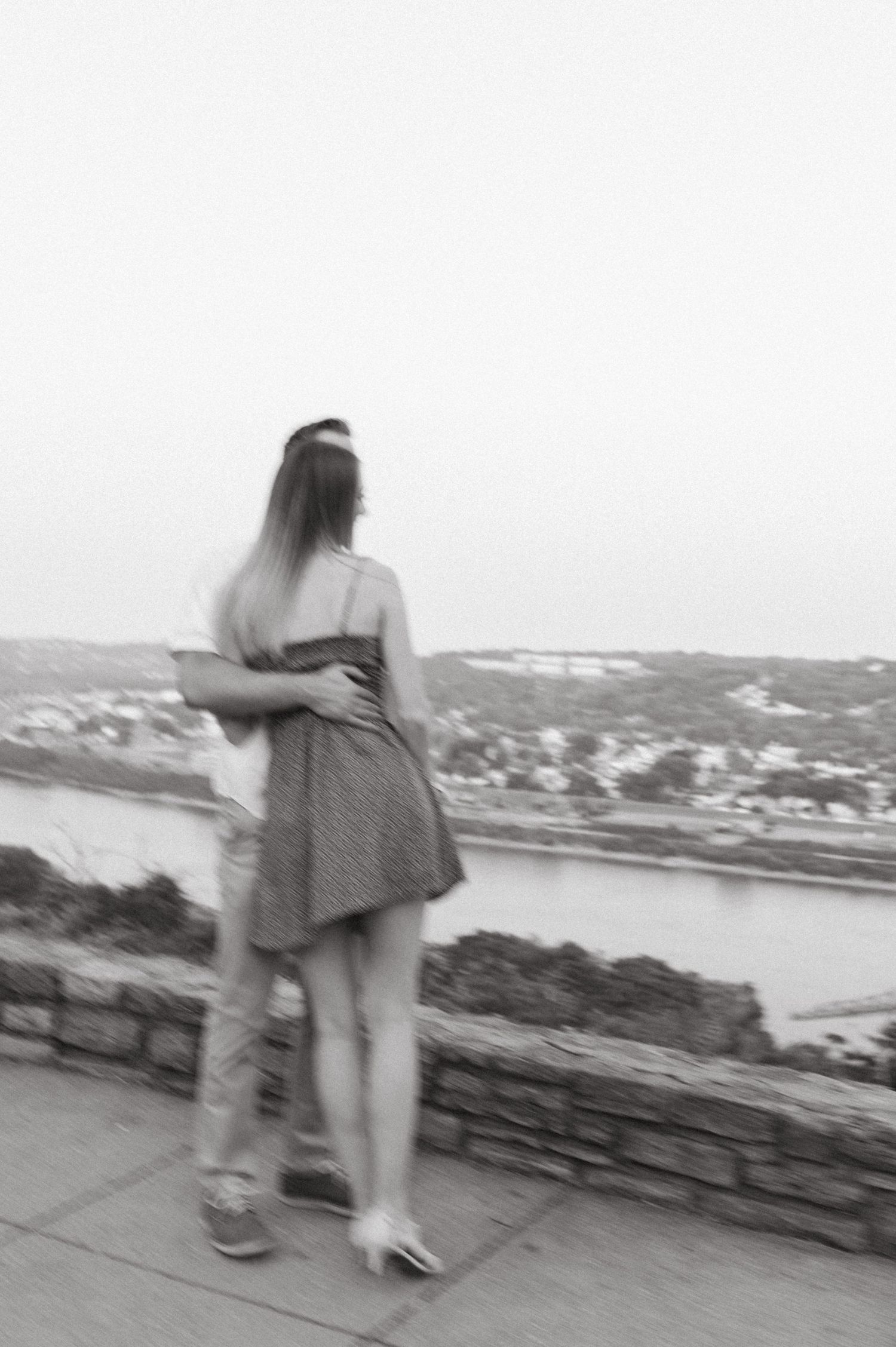 Blurred artistic black and white photo of couple embracing at scenic overlook.