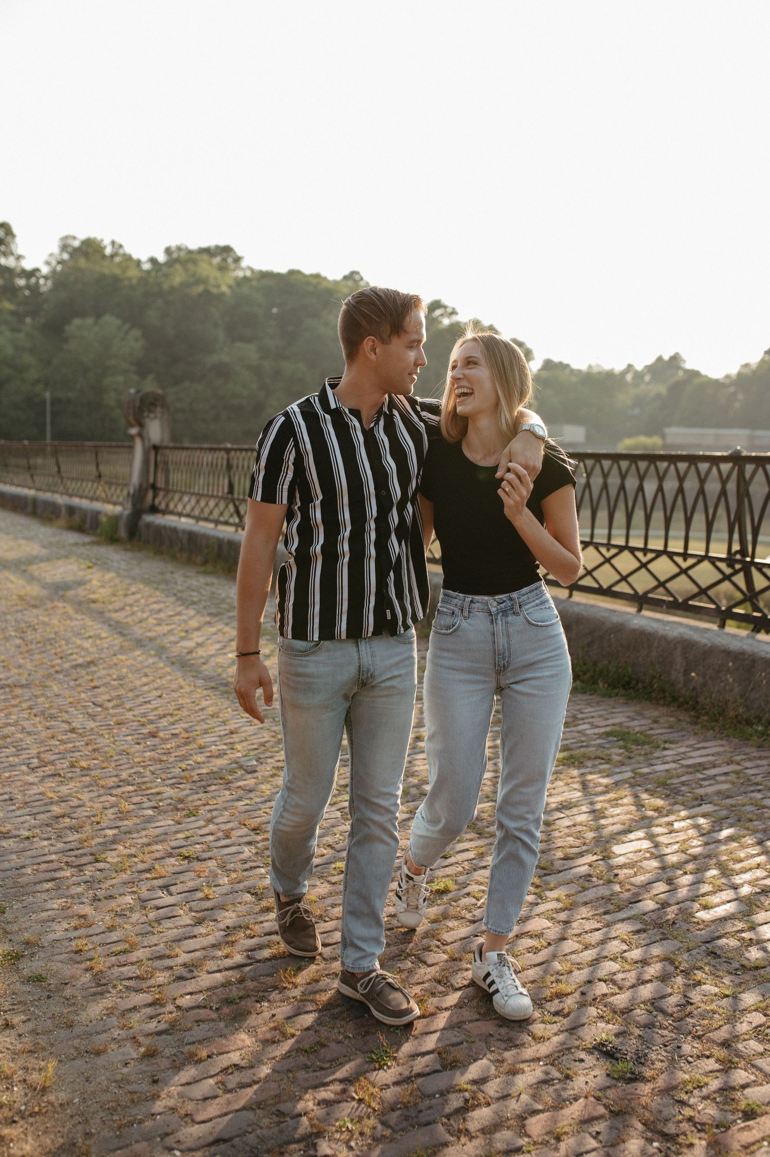 Happy couple walking together on a bridge during golden hour sunlight.