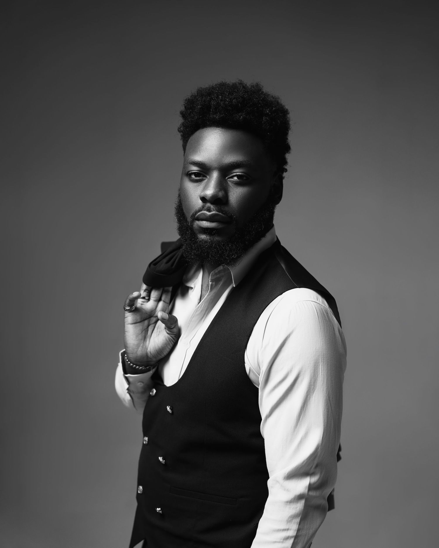 Professional studio portrait in black and white featuring dramatic lighting and formal attire.
