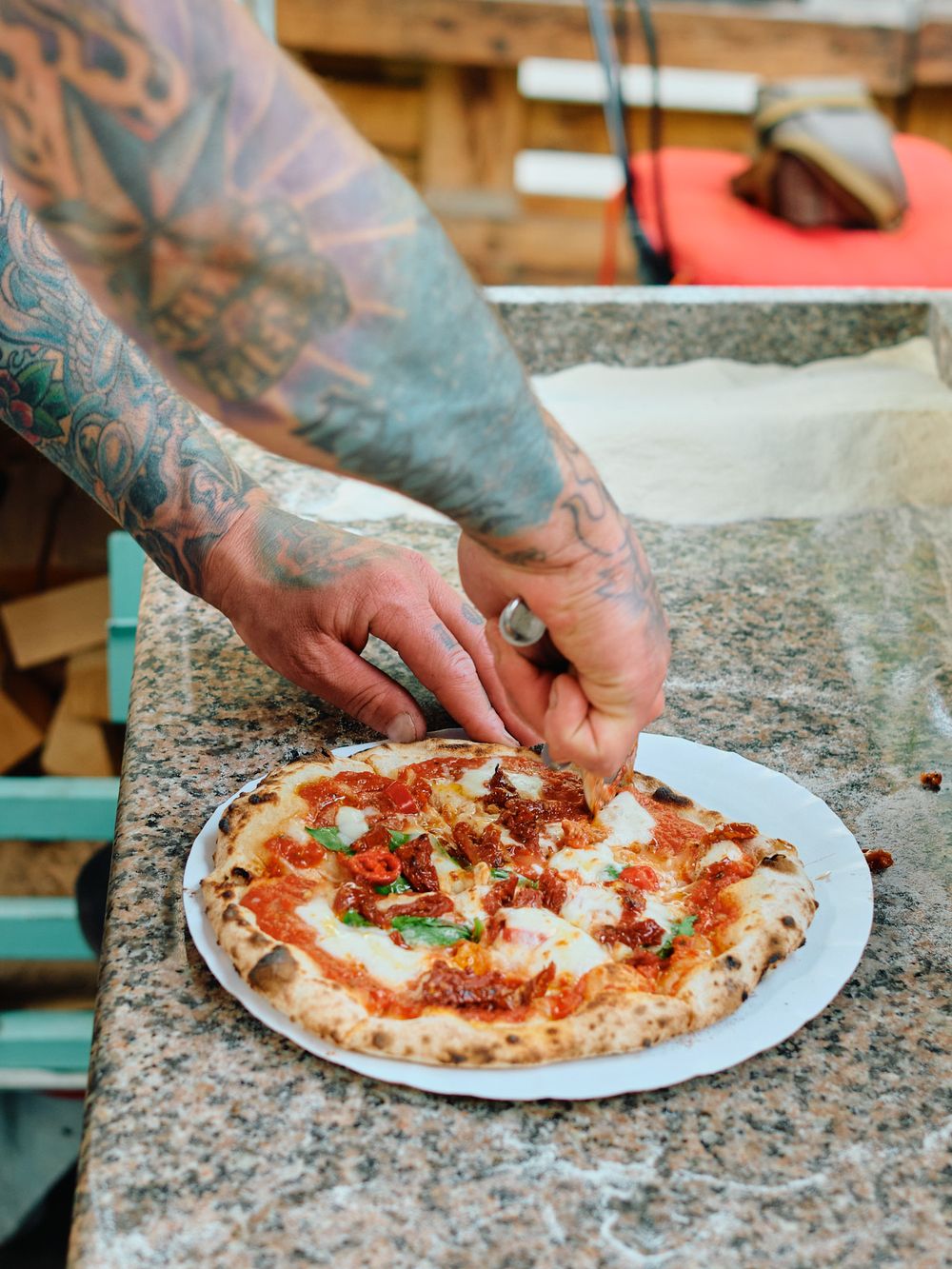 Preparing a fresh pizza with toppings on a granite countertop.