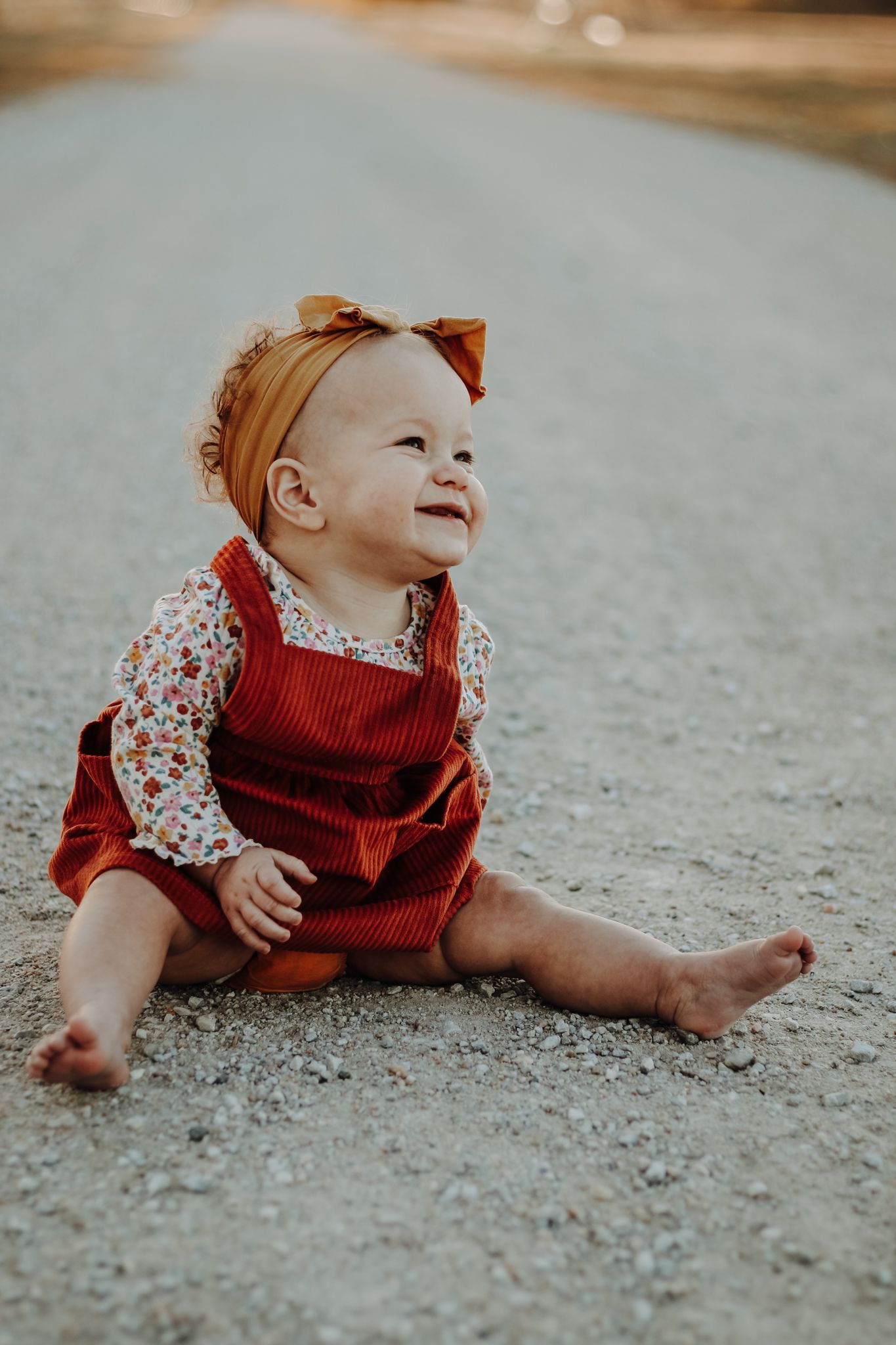 Baby in red outfit and floral dress crawling on carpet with joyful expression.