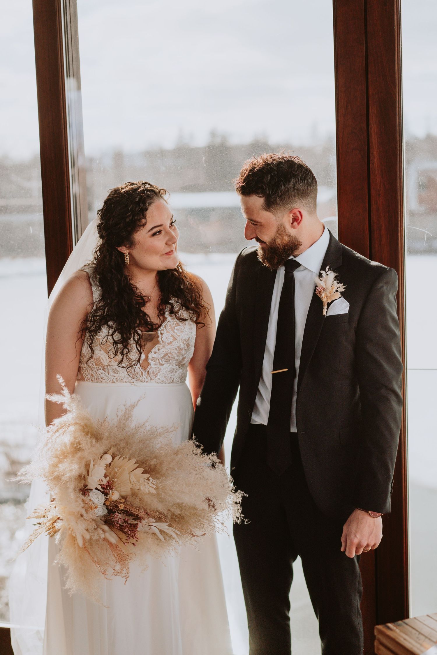 Image of bride and groom holding hands smiling at eachother.