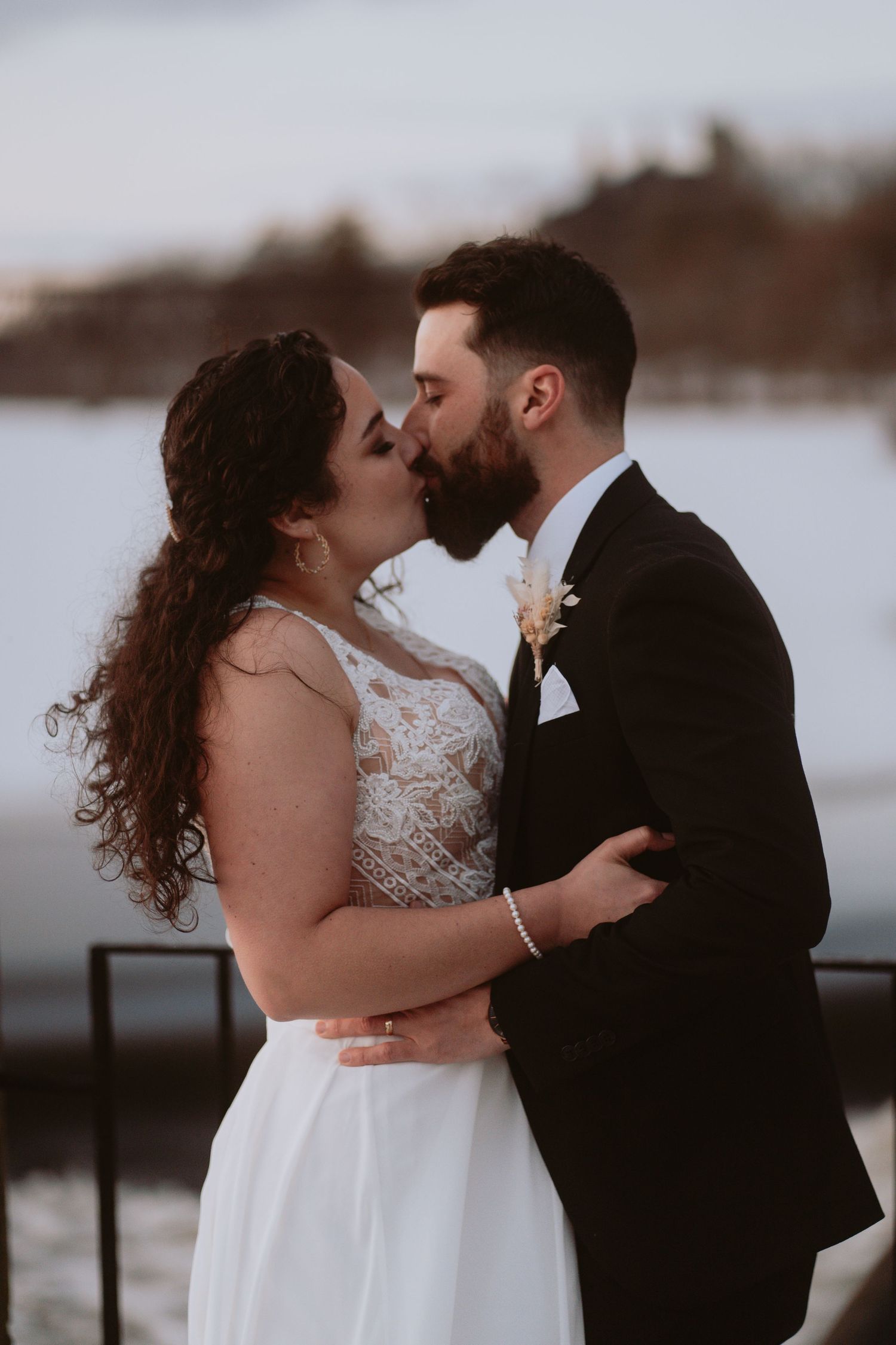 Image of bride and groom kissing in front of water.