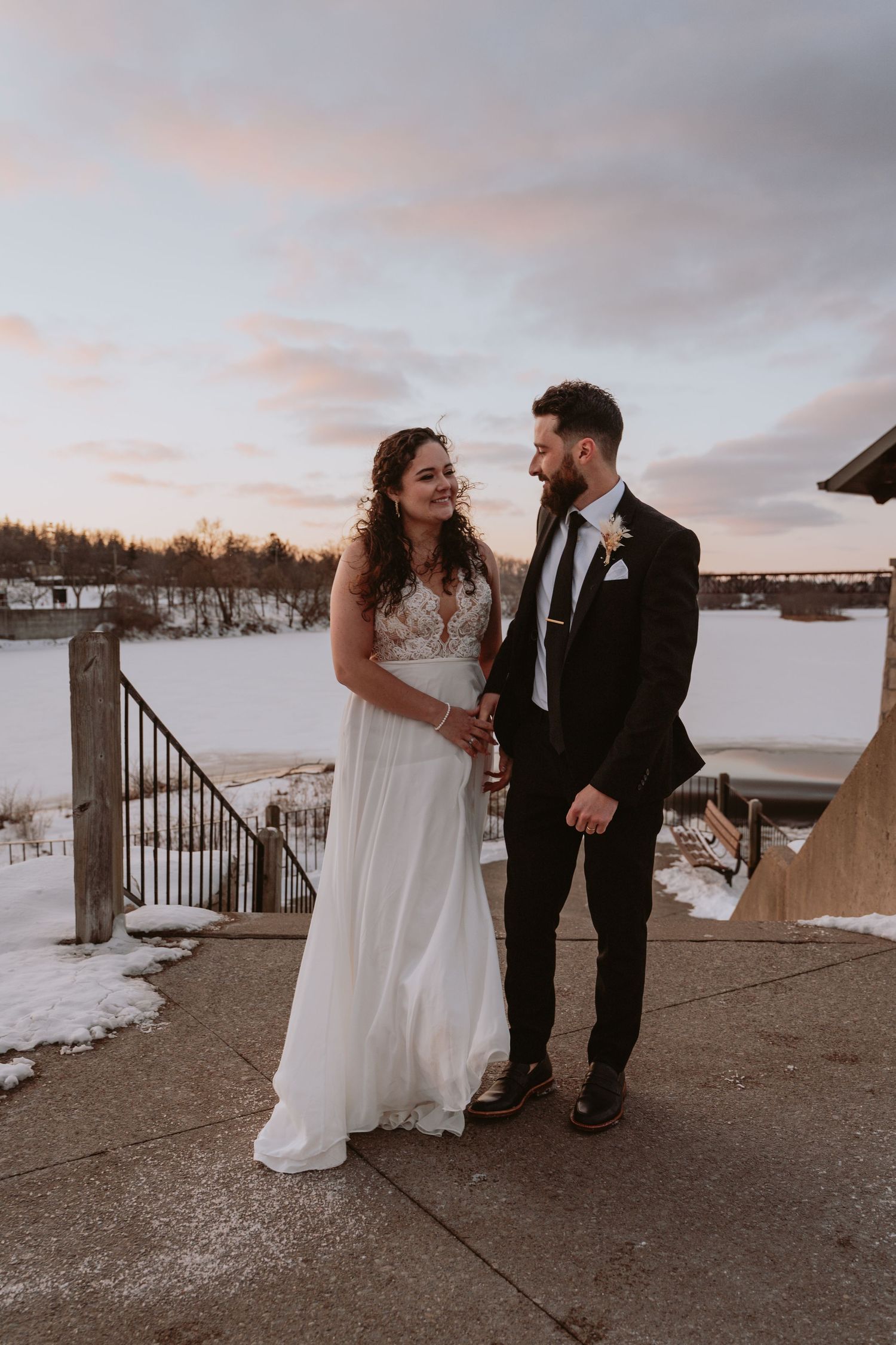 Image of bride and groom walking in front of water.