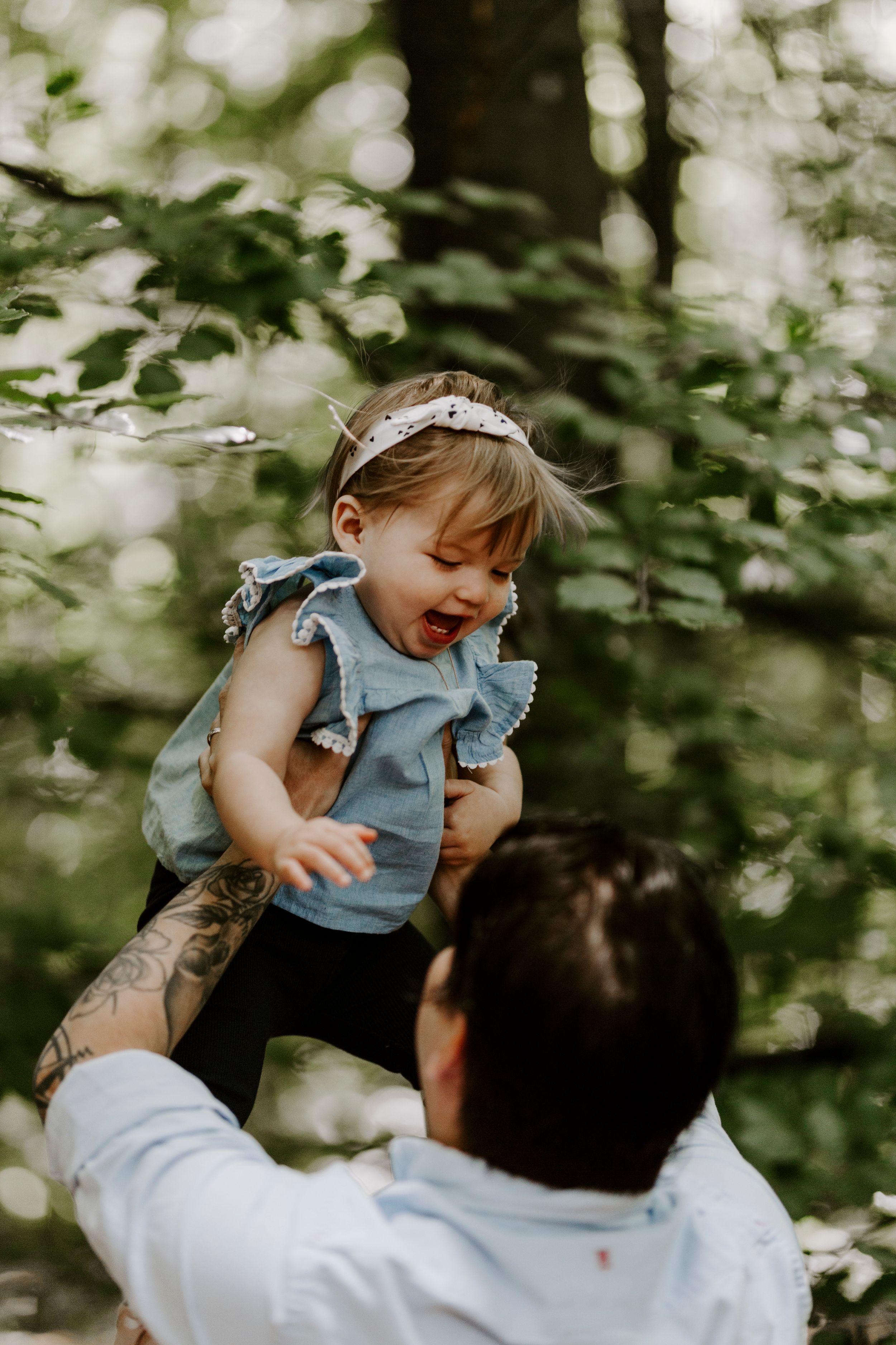 A joyful moment between parent and child playing in a forest setting with soft natural lighting.