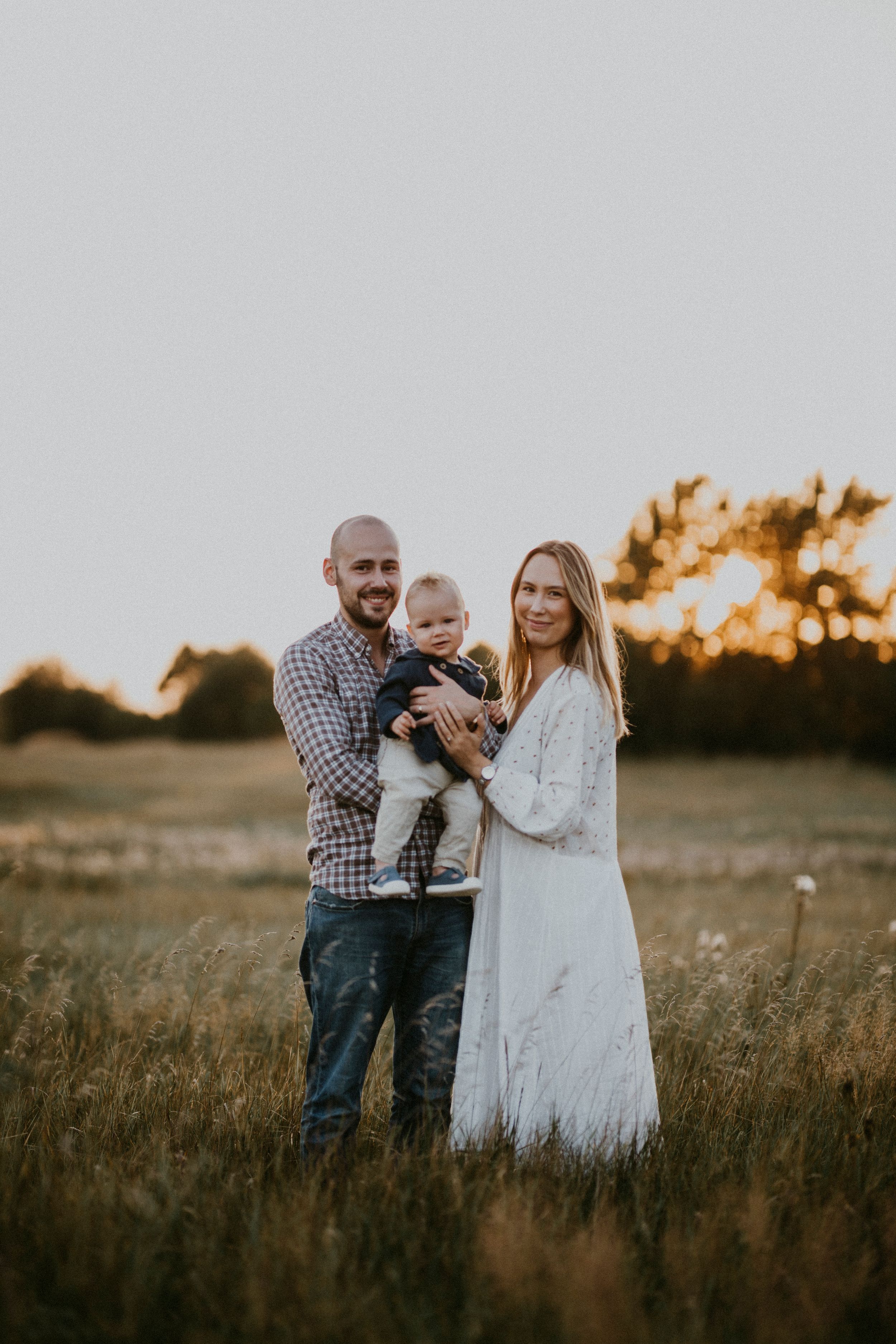 A family stands together in a field at sunset creating a warm silhouette.