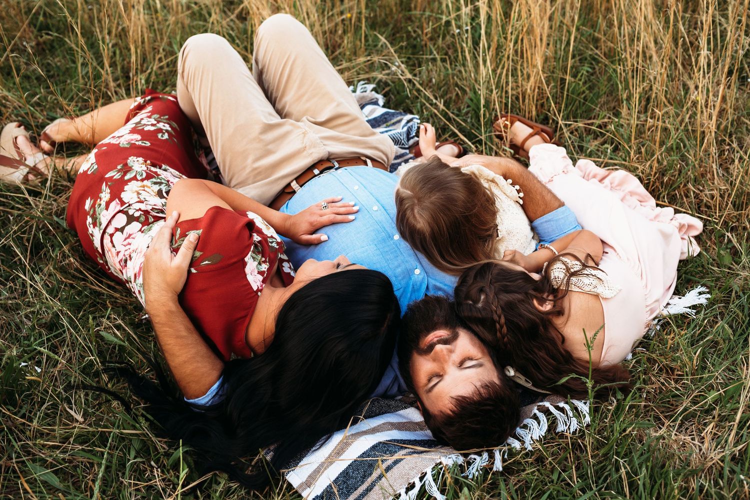 Family laying together on a blanket in the grass