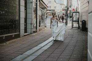 a model walking down an alleyway wearing a white wedding dress in silk in Brighton