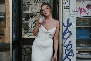 photo of a model leaning on a phone box drinking a coffee