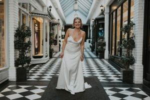 a model walking down an alleyway wearing a white wedding dress in silk in Brighton