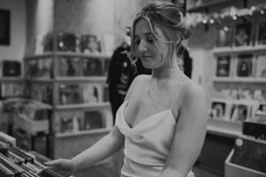 a black and white image of a model in a white silk wedding dress browsing records in a Brighton Record Shop