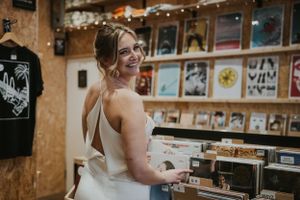a model in a white silk wedding dress browsing records in a Brighton Record Shop