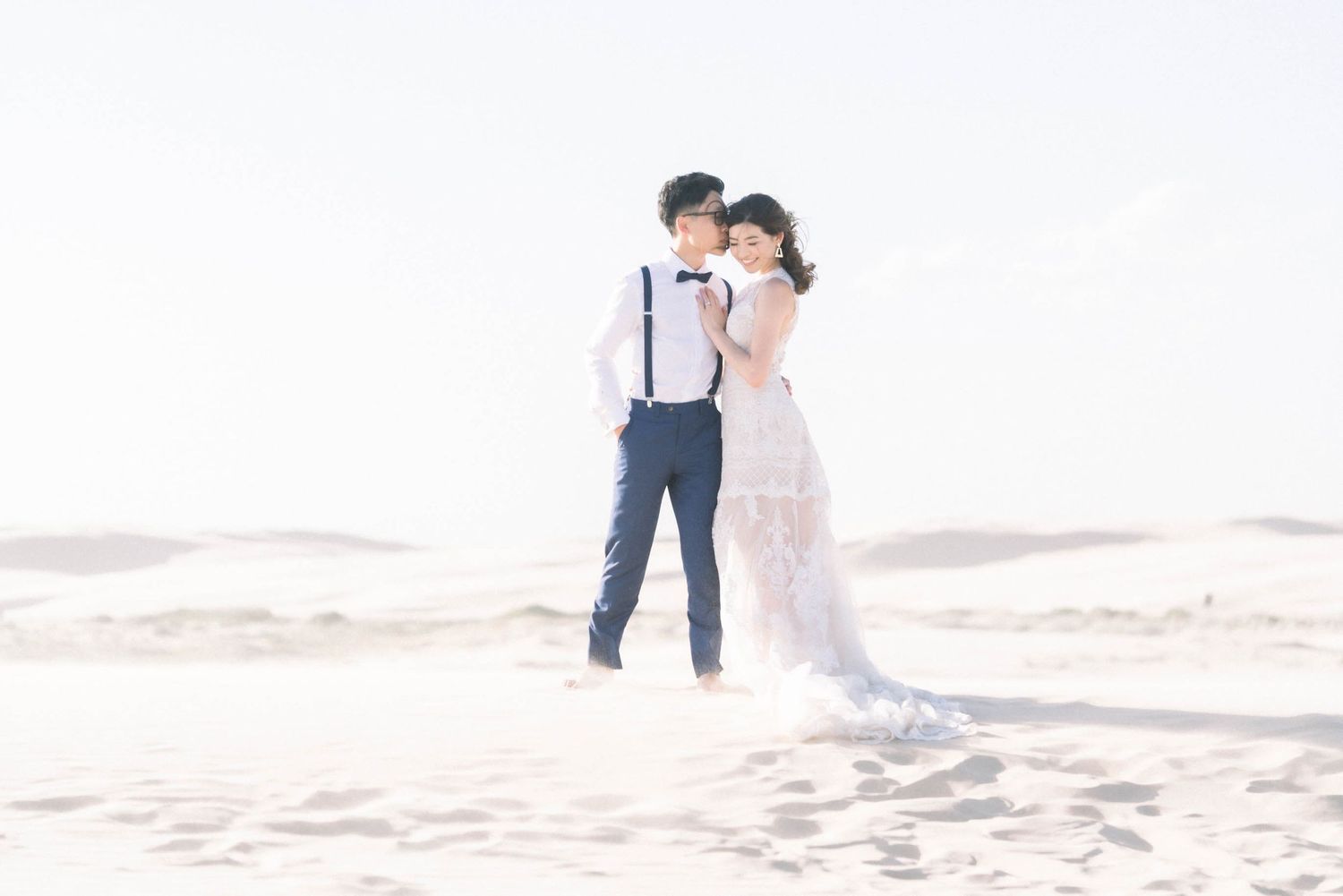 A romantic beach wedding portrait with soft dreamy lighting and sandy backdrop.