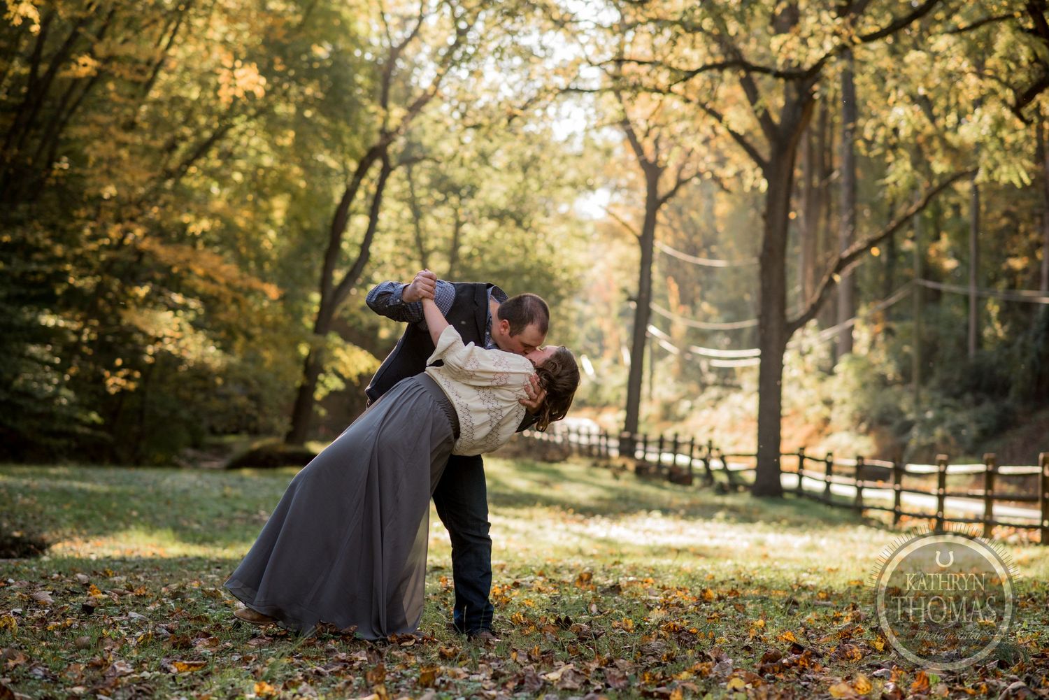 A romantic autumn portrait shows a couple embracing in a wooded setting with golden fall foliage.
