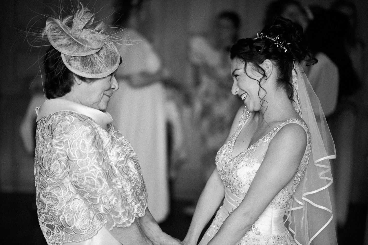 A touching black and white moment between two people in elegant wedding attire.