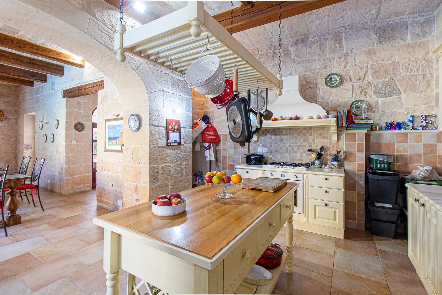 Rustic farmhouse kitchen with stone walls, wooden island, and traditional decor.