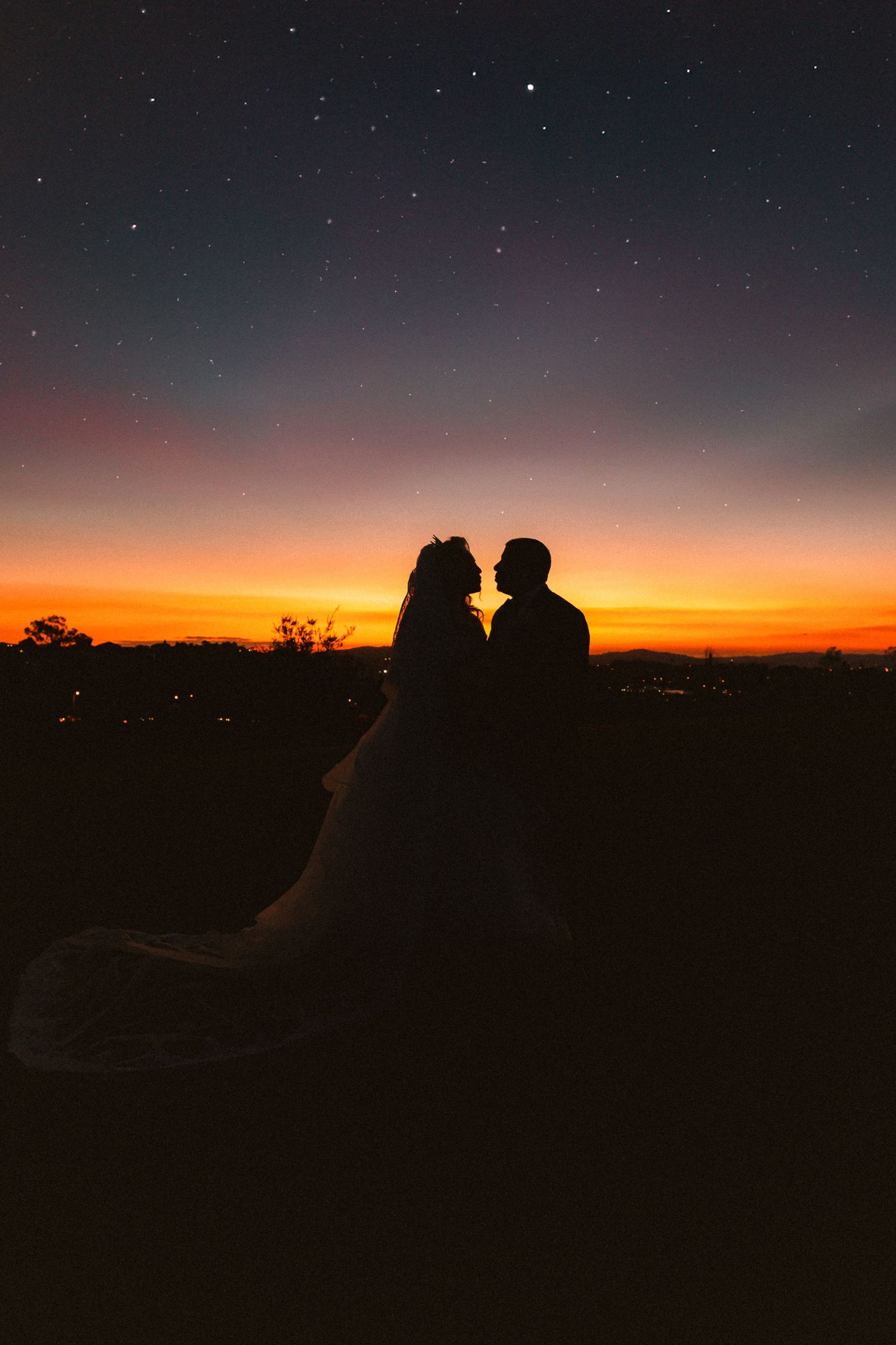 Romantic silhouette of newlyweds against starry sunset sky.