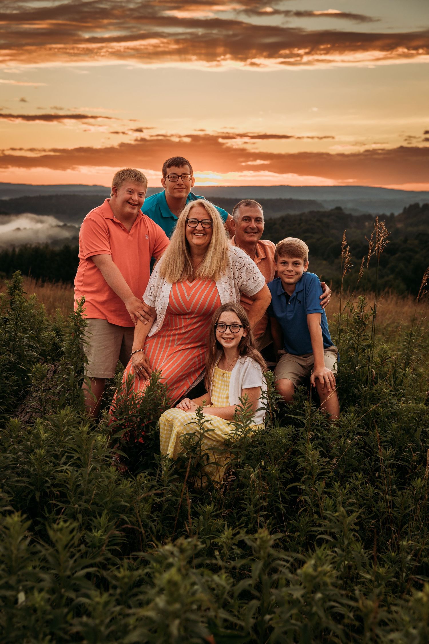 Family group photo taken at sunset with mountains and dramatic sky in background.