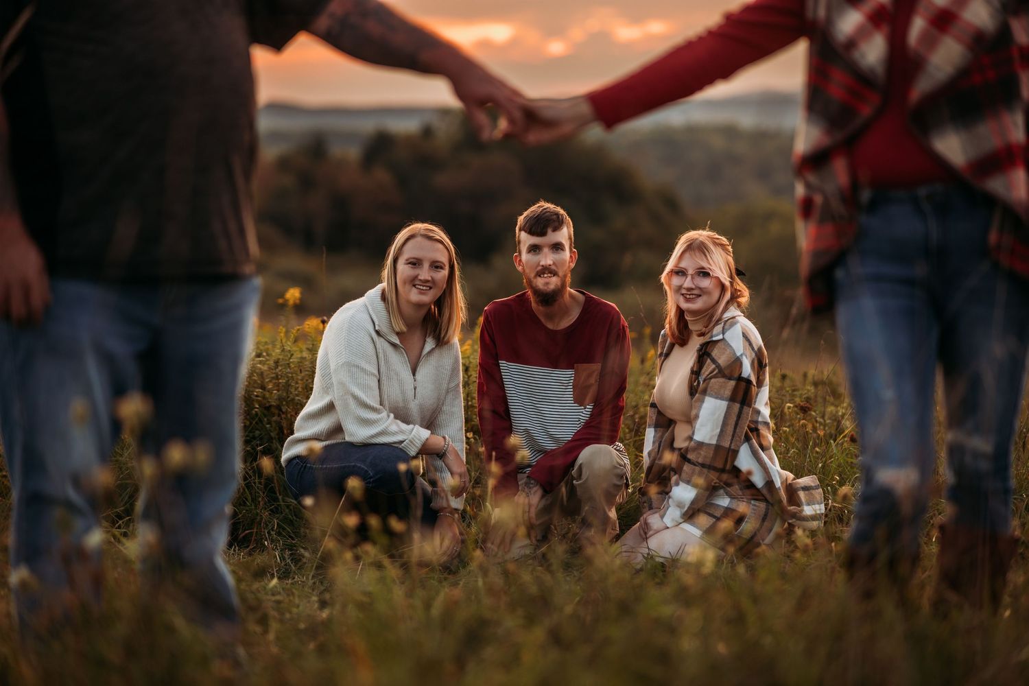 Group sitting together in golden wildflower field during sunset.