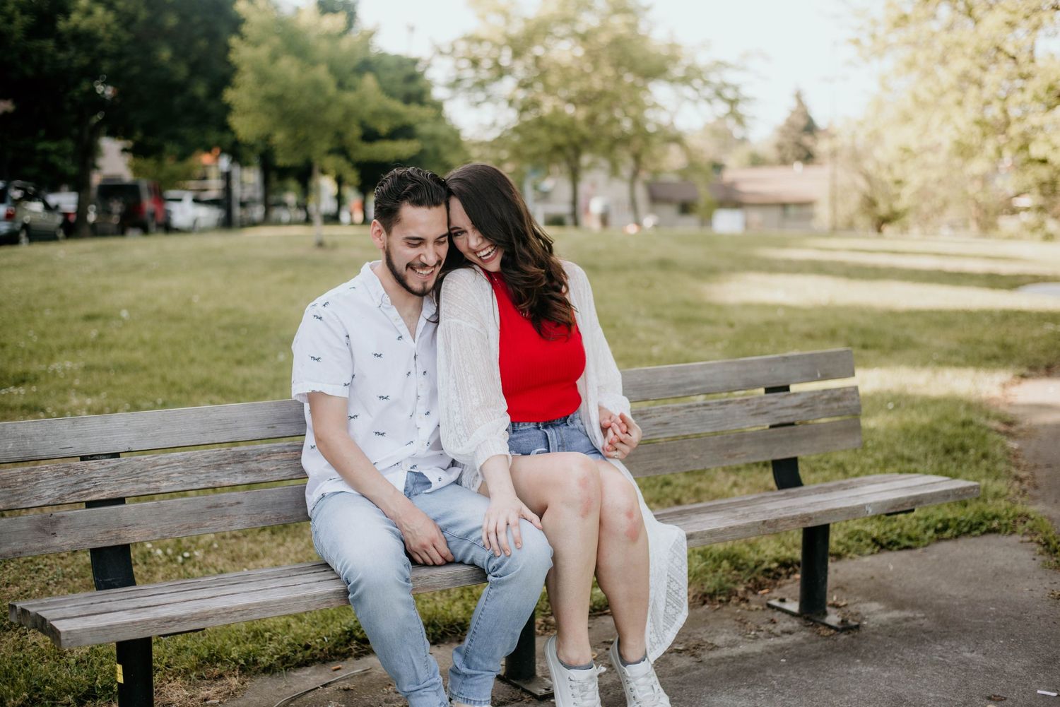 Couple sharing romantic moment while sitting on park bench during summer day.