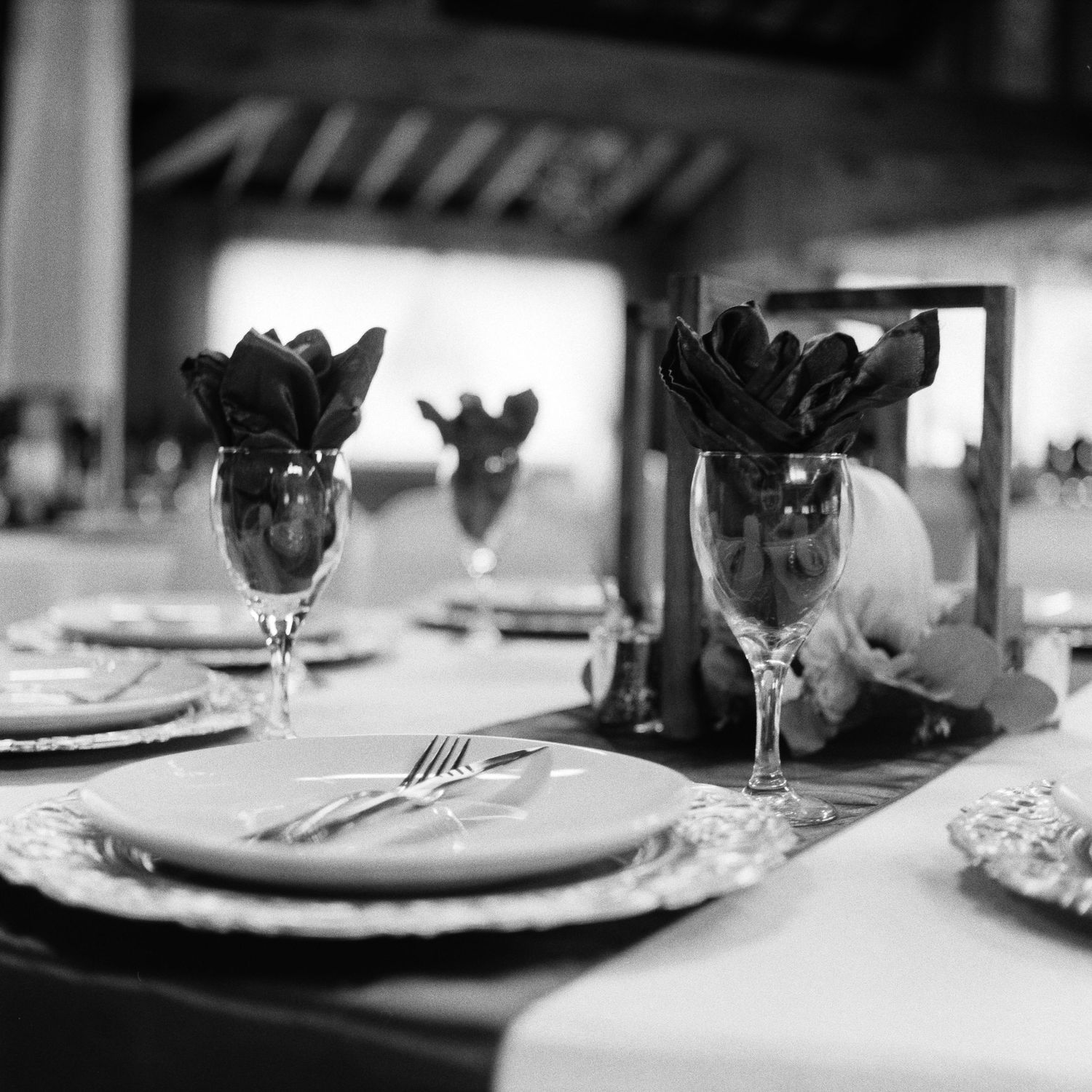 Black and white table setting with elegant place settings and floral centerpieces in wine glasses.