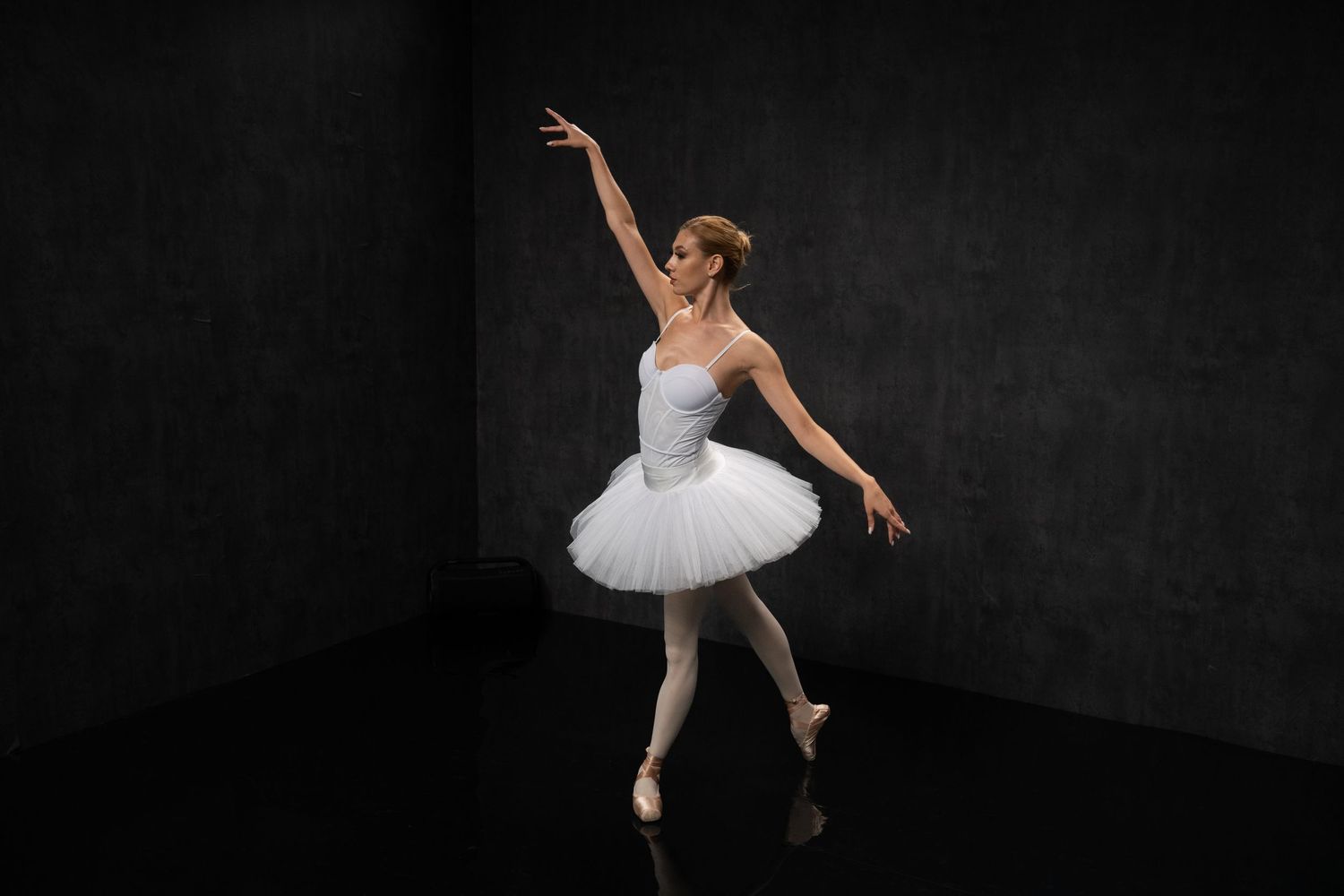 Graceful ballet performance captured in dramatic black and white studio setting.