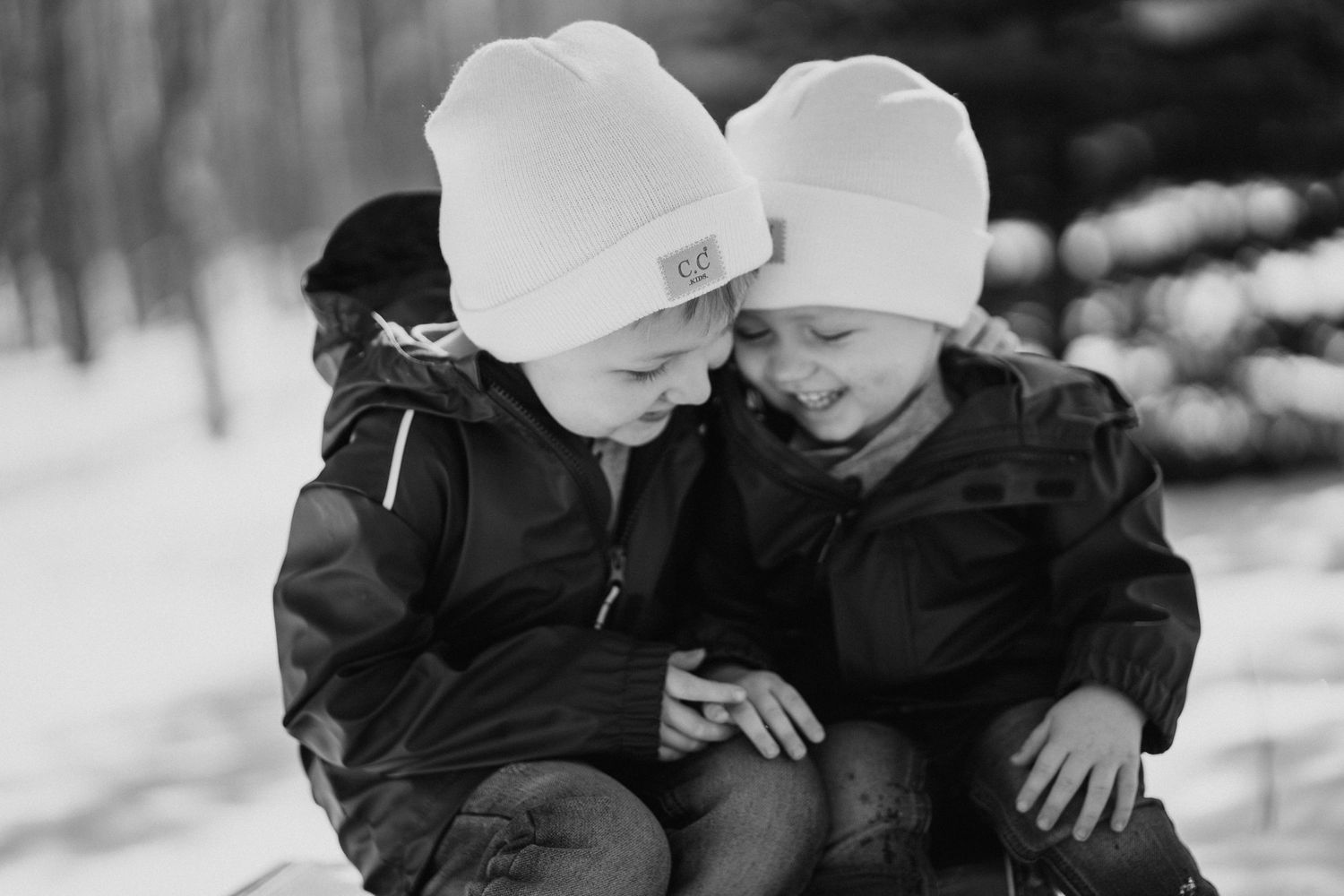 Two children bundled up in winter clothes share a sweet moment in the snow.