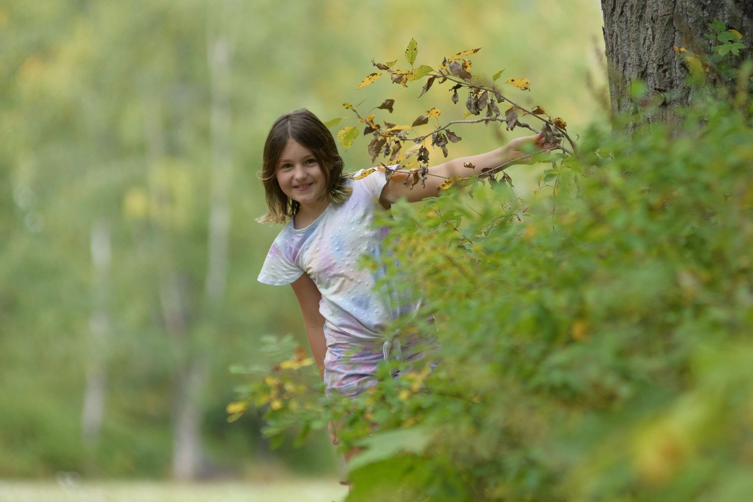 Candid summer portraits showing playful moments in a lush green outdoor setting.
