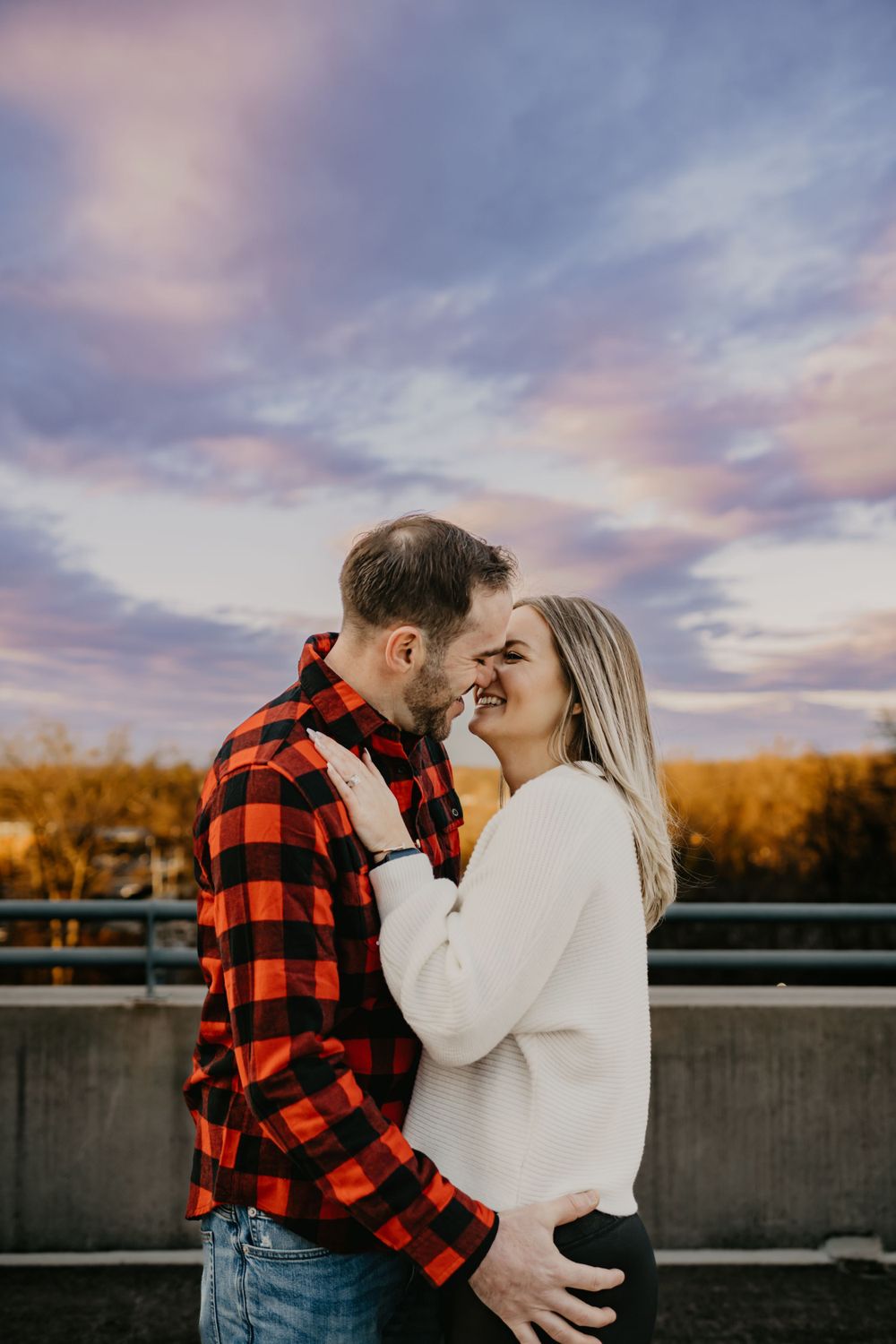 Intimate portrait of couple against purple sunset sky, with one wearing buffalo plaid.