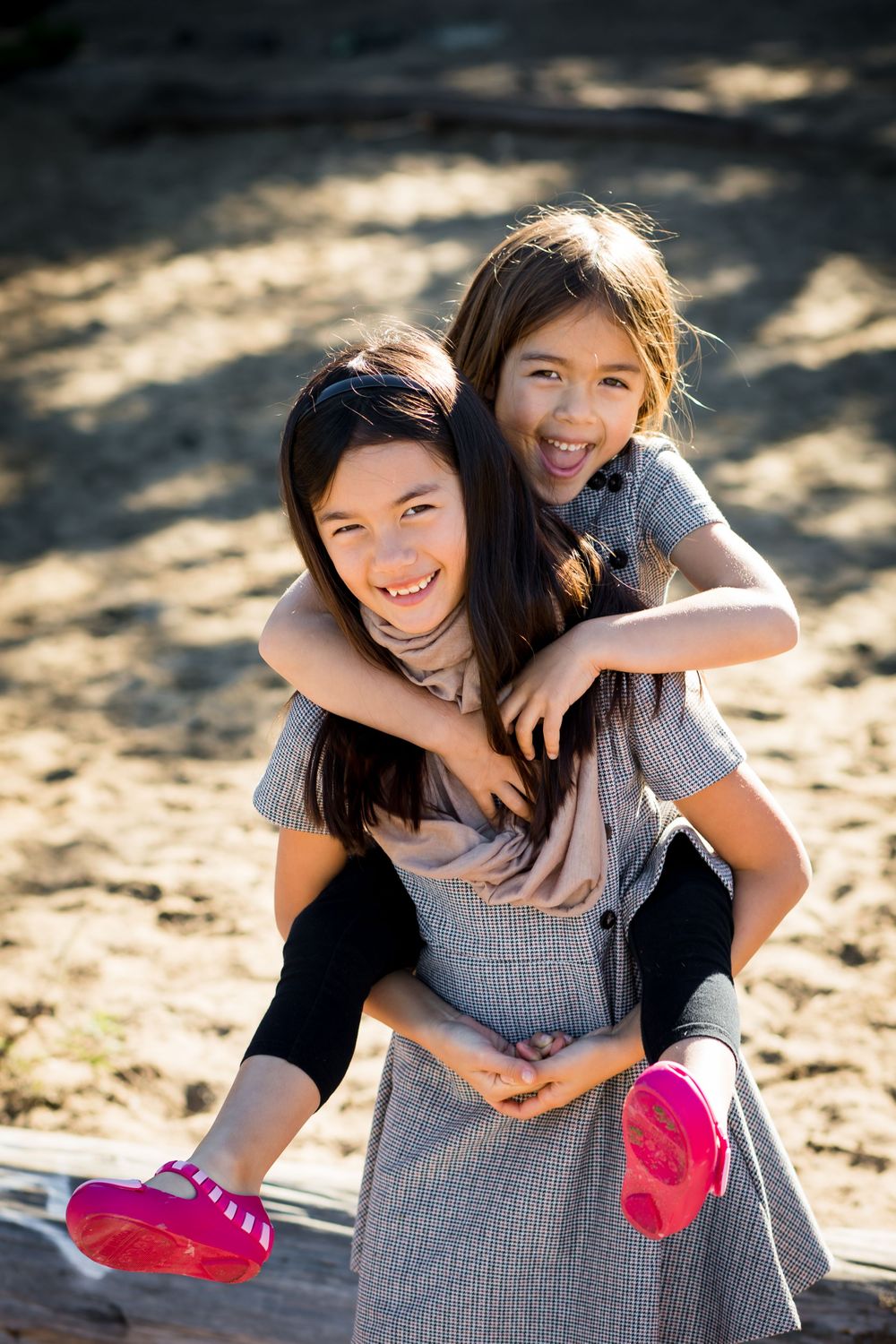 A playful piggyback ride portrait in sunlit outdoor setting.