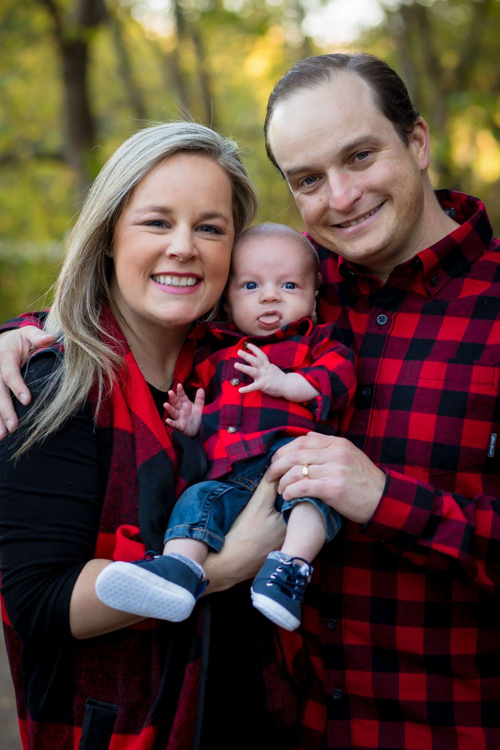 Family wearing coordinating red and black buffalo plaid outfits posing together outdoors.