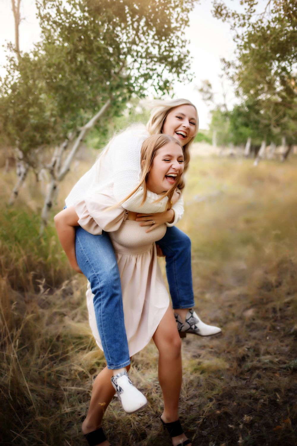 Two people share a playful piggyback ride moment among trees in natural lighting.