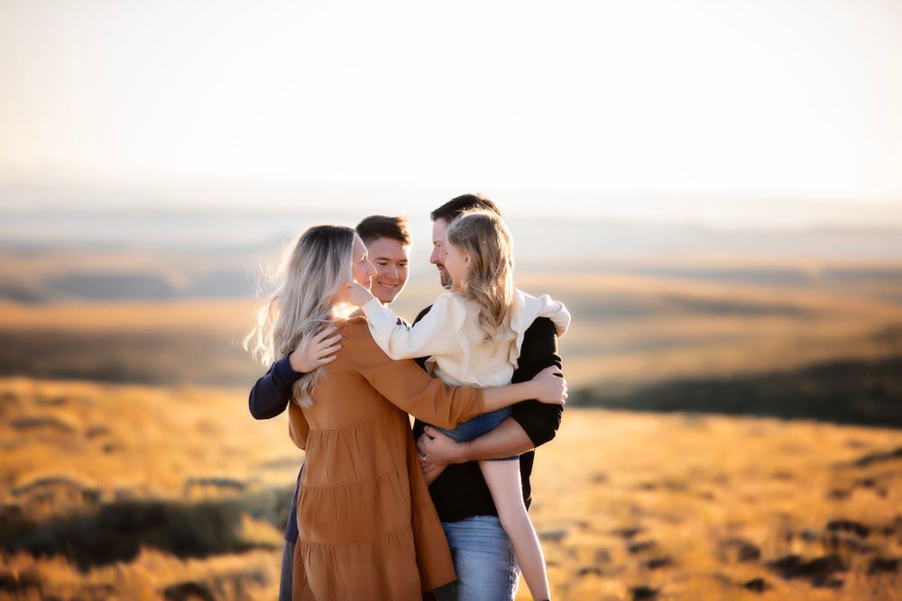 A family shares a warm embrace during golden hour in an expansive desert landscape.