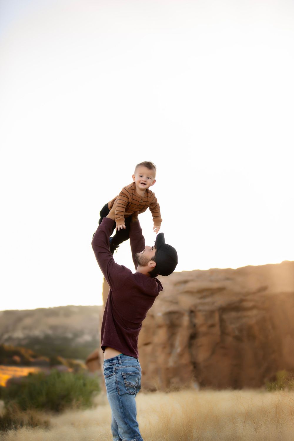 A playful moment between parent and child against desert rock formations at sunset.
