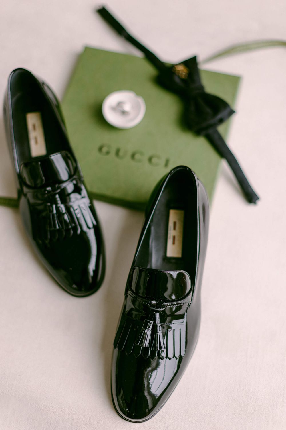 Patent leather Gucci loafers with tassels displayed with their signature green box.