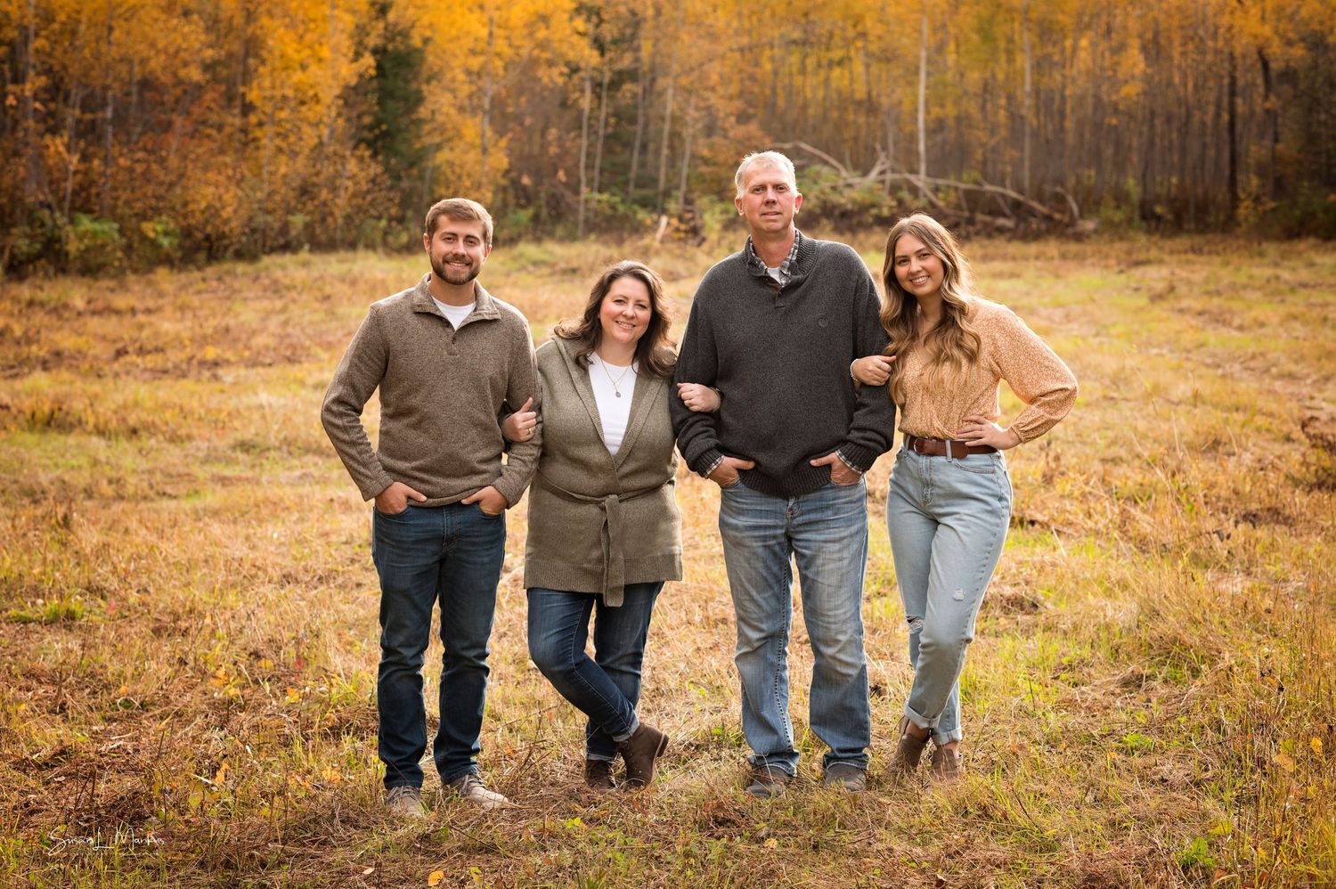 Family of four with grown children on fall background in Orr, Minnesota.