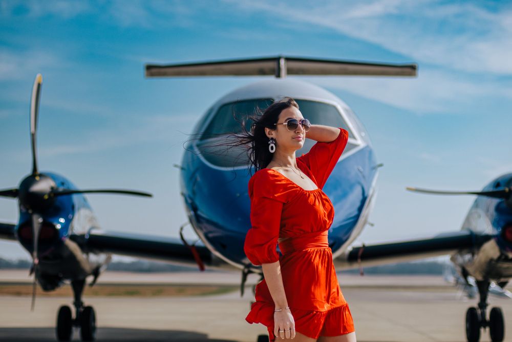 Red dress against blue sky with small aircraft in background at airfield.