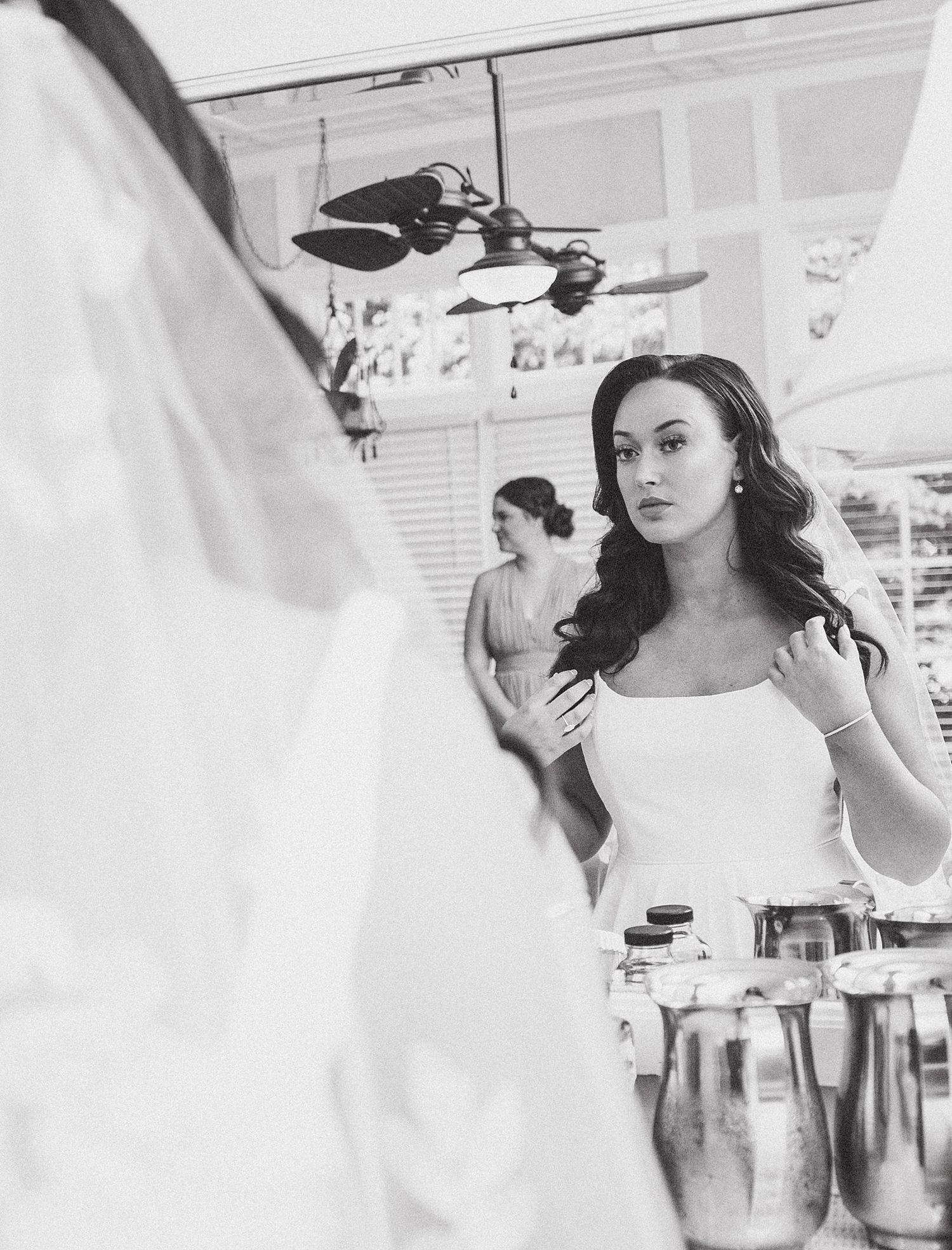 Black and white image of wedding preparations in an elegant room with chandelier lighting.
