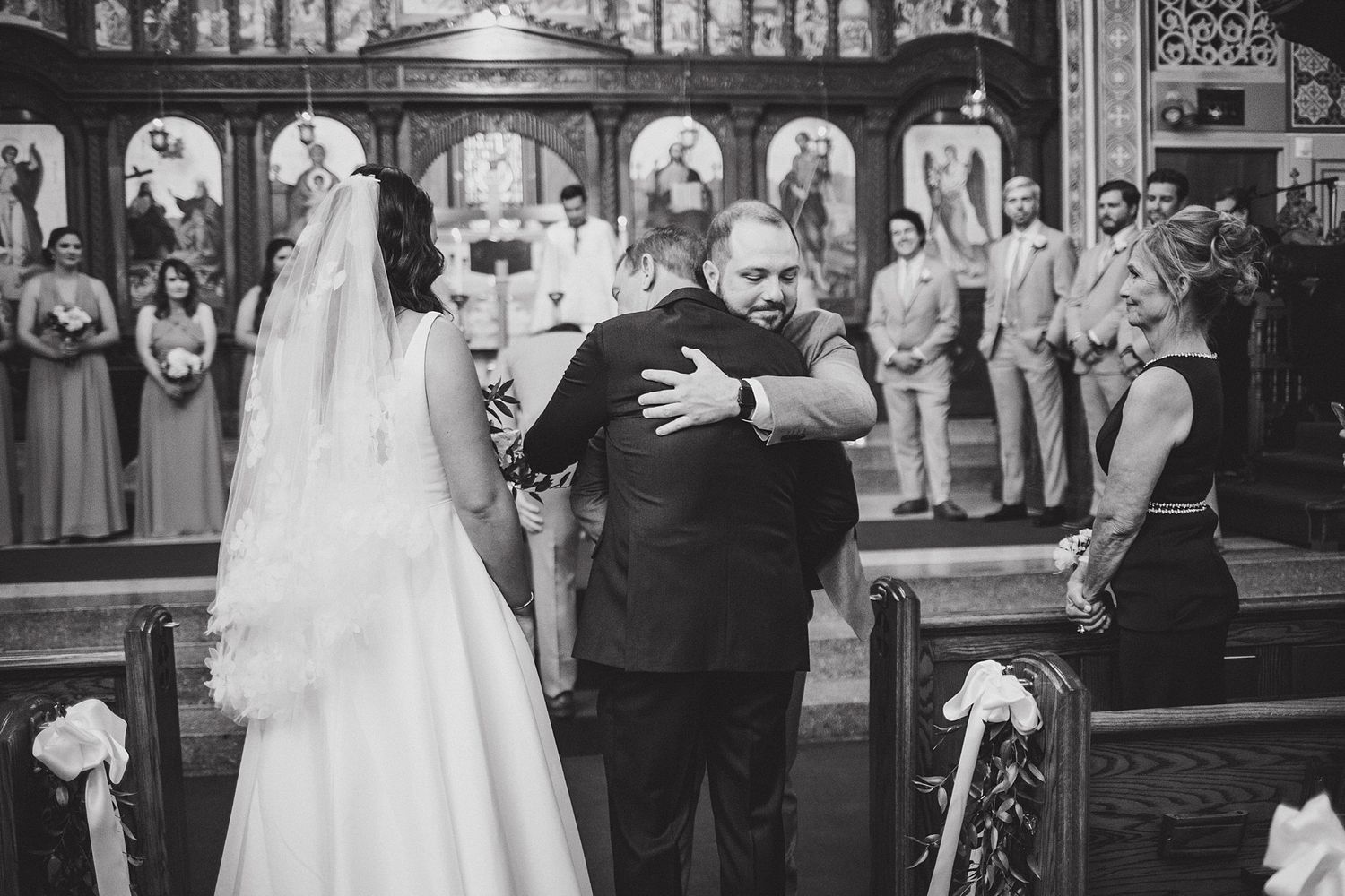 Wedding ceremony in progress at an ornate church altar with wedding party looking on.