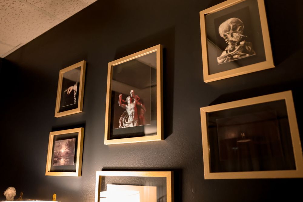 Vintage-style framed photographs arranged on a dark wall in golden frames.