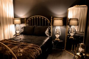 Luxurious bedroom with brass bed frame and crystal table lamps in warm atmospheric lighting.