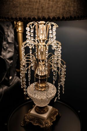 Ornate crystal chandelier table lamp with cascading beads and golden accents on decorative base.
