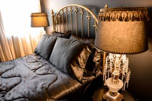 Elegant bedroom featuring crystal table lamp and brass bed frame with dark bedding.