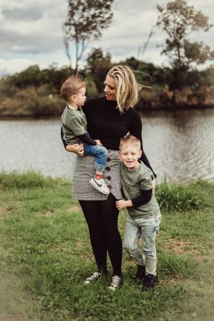 A casual outdoor family portrait by a lake with everyone wearing coordinated outfits.