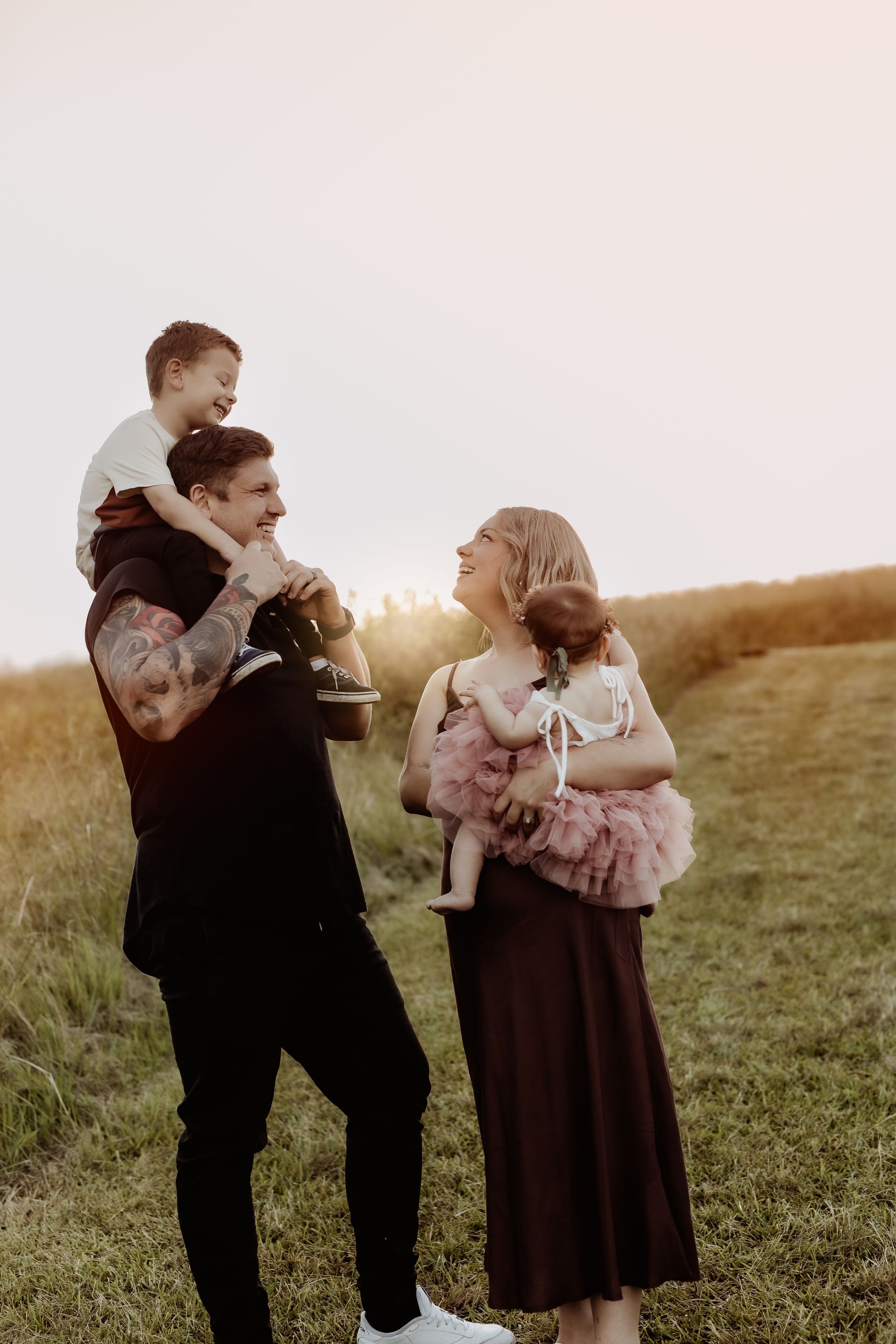 Family sharing tender moments together in a grassy field during golden hour.