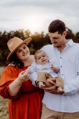 Family outdoor photoshoot with warm tones featuring tender moments and white clothing.