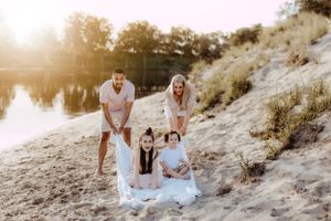 Family spending time together on sandy dunes during sunset.