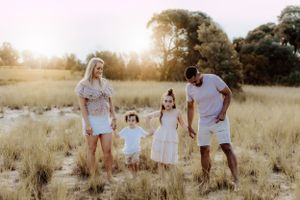 Family walking together through a sunlit field during golden hour.
